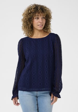 Blouse à manches longues bleu marine en tissu dentelle texturé à motif losange. Dotée d'un col rond et de poignets froncés.