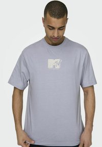 Lyslilla bomulds T-shirt med et hvidt MTV-logo i rektangulært design på brystet. Korte ærmer og rund halsudskæring.