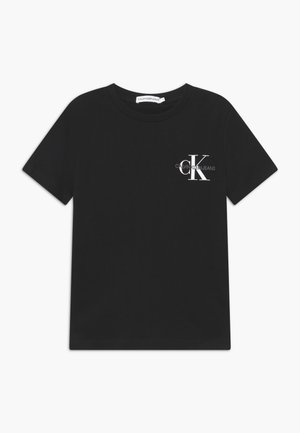 Camiseta negra de manga corta con cuello redondo y pequeño logo "Calvin Klein Jeans" en blanco y gris en el lado izquierdo del pecho.