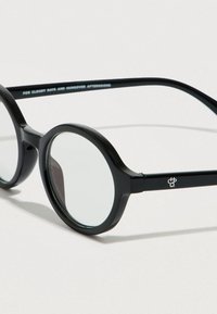 Okrągłe okulary przeciwsłoneczne z czarnymi plastikowymi oprawkami i przezroczystymi szkłami. Na zausznikiem znajduje się logo z napisem: „NA POGODNE DNI I POPOŁUDNIA Z KACEM.”