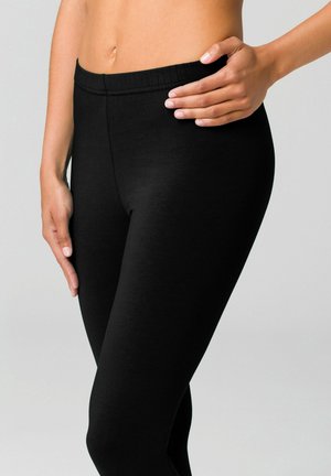 Schwarze Leggings bestehen aus einem glatten, dehnbaren Stoff mit einem hohen elastischen Bund, der für Komfort und eine enganliegende Silhouette ausgelegt ist.