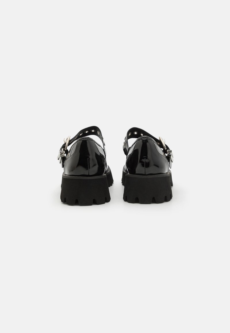 Scarpe in pelle verniciata nera con suola spessa, caratterizzate da un design slingback, dettaglio fibbia e borchie sulla cinghia.