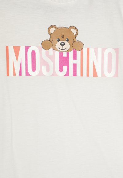 Maglietta bianca con grafica di un orso marrone sopra il logo "MOSCHINO" in lettere multicolori su uno sfondo semplice.
