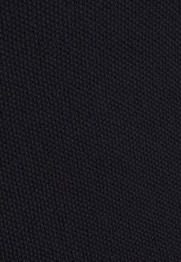 Texturerad svart tyg som visar ett tajt mönster, tillverkat av ett mjukt material som är lämpligt för kläder eller möbelklädsel.