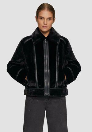 Schwarze Kunstpelzjacke mit einem breiten Kragen, vorderem Reißverschluss und Lederelementen. Hat eine kastige Passform und eine weiche Textur.