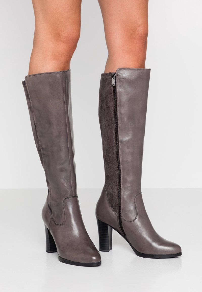 Bottes en cuir gris montantes avec une fermeture éclair sur le côté, des panneaux en daim texturé et un talon épais. Finition lisse et silhouette élégante.