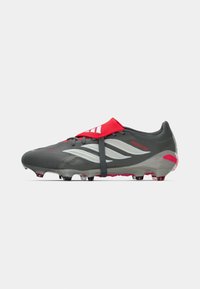 Gray soccer cleat with red accents, featuring a smooth upper, rubberized sole, and three-stripe branding. Includes a black elastic strap.
