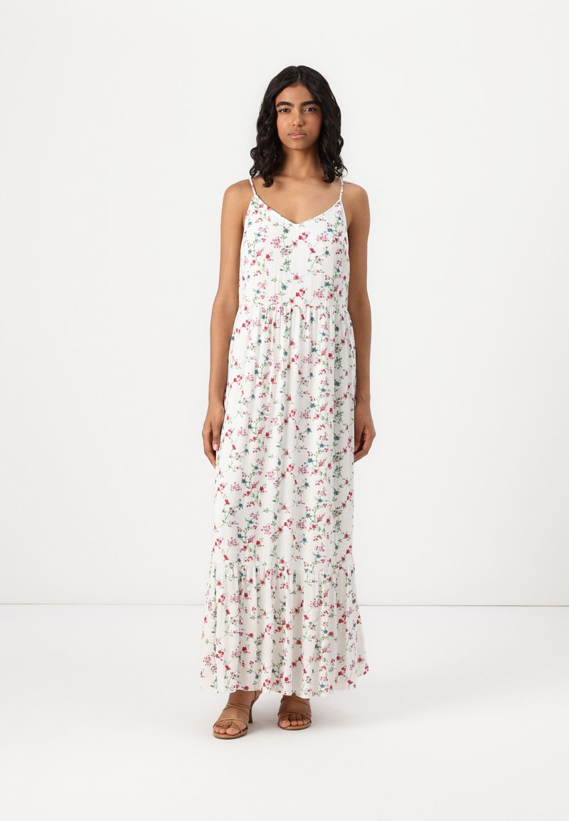 Blommig maxiklänning i vit tyg, med rosa och gröna blommor, spagettiaxlar, en åtsittande bodice och volangkant i flera lager.