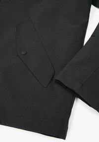 Giacca nera con una texture liscia e opaca, dotata di una tasca inclinata distintiva e rifiniture pulite sui polsini.