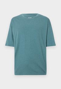 Zöld pamut póló kerek nyakkivágással és rövid ujjakkal. Lazán illeszkedő fazon, texturált felülettel, látható minták vagy díszítések nélkül.