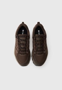 Brown textured sneakers with mesh and suede materials. Features orange-accented laces, logo on insoles, and a low-profile rubber sole.