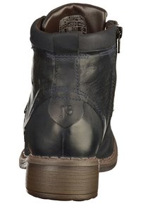 Ciemnoniebieski skórzany botek za kostkę z bocznym zamkiem błyskawicznym, teksturowana powierzchnia i brązowy, warstwowy obcas. Posiada wytłoczone inicjały "JS" na obcasie.