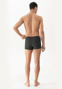 Boxer shorts en tissu noir avec un motif en quadrillage. Taille élastique, style ajusté, texture lisse et longueur de jambe courte.