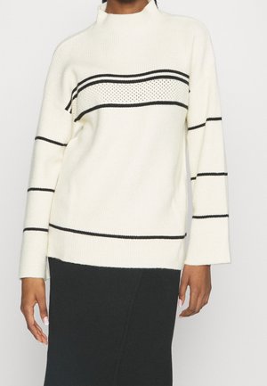 Weißer Strickpullover mit schwarzen horizontalen Streifen. Merkmale einen hohen Kragen und eine gerippte Textur. Lange Ärmel und lockere Passform.
