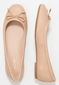 Ballerine in pelle beige con punte arrotondate, piccoli fiocchi decorativi con punte dorate e suole piatte in gomma, viste dall'alto e di lato.