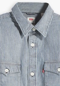 Μπλε και λευκό ριγέ πουκάμισο με γιακά με κουμπιά, δύο μπροστινές τσέπες και λευκά κουμπιά. Το ετικέτα της Levi's είναι ορατή στον γιακά.