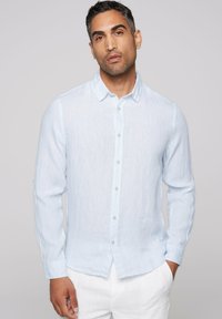 Camisa de botones azul claro en una tela texturizada, con cuello, mangas largas y dobladillo recto. Incluye botones blancos y un diseño minimalista.