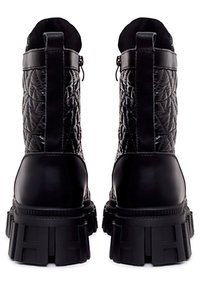 Botines negros con textura acolchada, suela de plataforma resistente y una lengüeta en la parte trasera para facilitar el calzado.