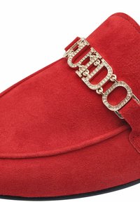 Červená semišová slip-on obuv s zlatým řetízkovým hardwarem a krystalovými akcenty po celé horní části. Hladká textura s designem zaoblené špičky.