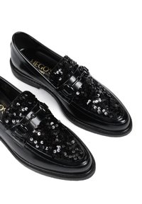 Czarne półbuty z błyszczącej lakierowanej skóry, ozdobione czarnymi cekinami na cholewce i podwójnymi zapięciami na klamry.
