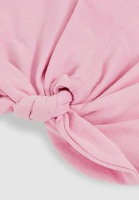 Top atado con nudos en tejido rosa suave, con una textura suave y un diseño torcido casual, además de costuras limpias a lo largo de los bordes.