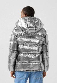 Zilveren donsjack met een glanzende textuur, voorzien van een capuchon, horizontaal doorgestikt ontwerp en elastische manchetten.