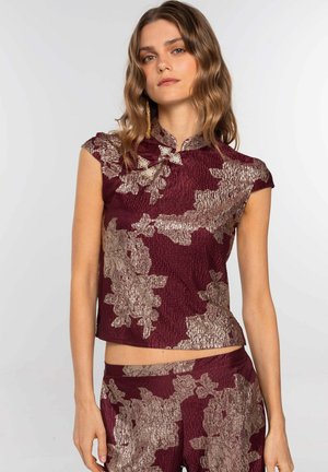 Top corto burdeos con patrón floral dorado. Cuenta con un escote alto y mangas de capullo, fabricado con un tejido texturizado. Combinado con una parte inferior a juego.