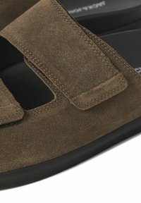 Sandal in suede marrone con due cinturini regolabili, suola in gomma nera e design aperto per una migliore traspirabilità.