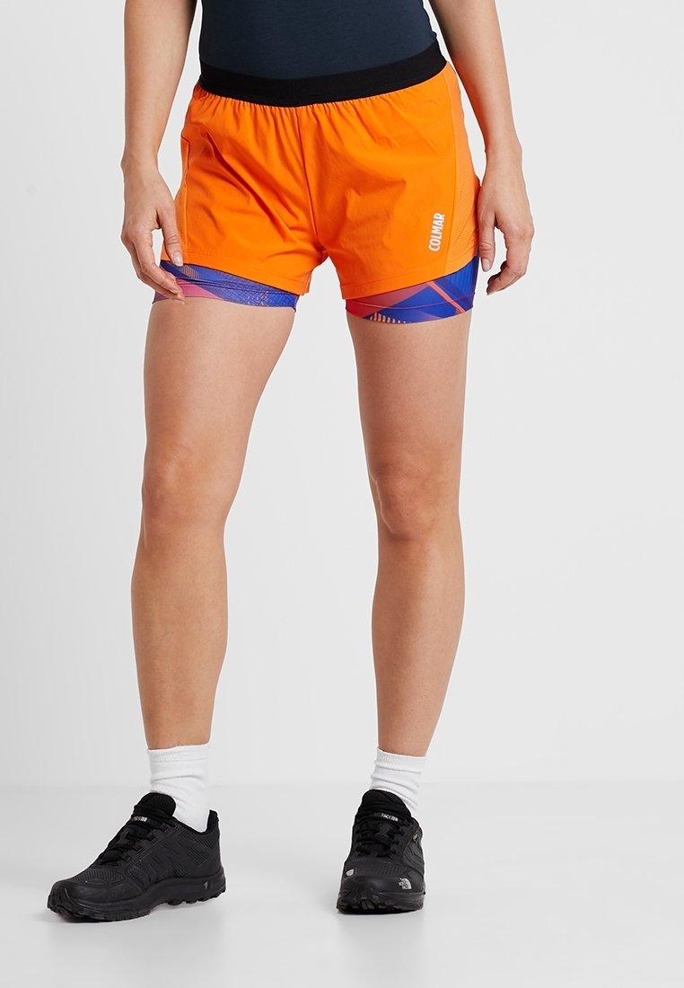 Korta orangea sportshorts med svart midjeband, som har blå mönstrade detaljer på sidorna och en lätt textur.