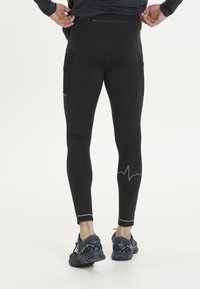 Sorte atletiske leggings lavet af strækbart stof med mesh-lommer, reflekterende detaljer og en hjertefrekvenslinje grafik nær kanten.