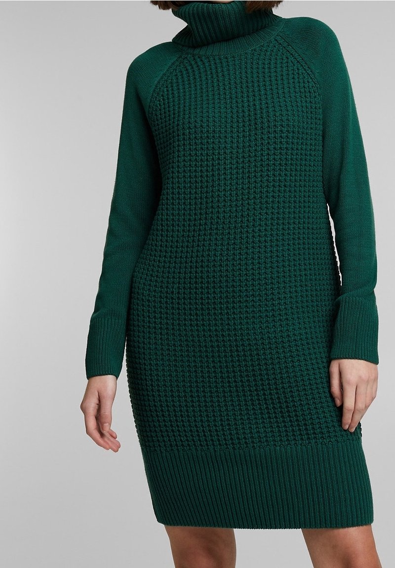 Robe en tricot verte avec col roulé, présentant un motif texturé sur le haut du corps et des détails côtelés aux poignets et à l'ourlet.