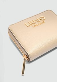 Portafoglio in pelle beige con hardware dorato e finitura testurizzata. Caratterizzato da una chiusura a zip e logo "LIU.JO MILANO" in rilievo sul davanti.