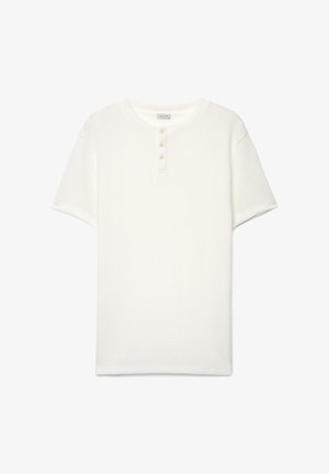 Weißes kurzärmeliges Frotteehemd mit rundem Ausschnitt und drei Knöpfen vorne, als flache Lage auf weißem Hintergrund.