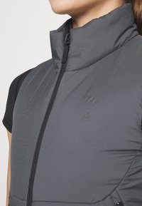 Κοντινό πλάνο ατόμου που φοράει γκρι επένδυση με φερμουάρ, με διακριτό κοσκινισμένο μοτίβο και το λογότυπο της Puma στο στήθος.