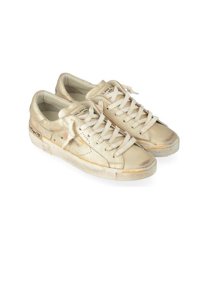 Sneaker metallici oro con punta rotonda, lacci piatti, tomaia testurizzata e suole in gomma bianca che mostrano un leggero usura. Accentuati con perforazioni e marchi.