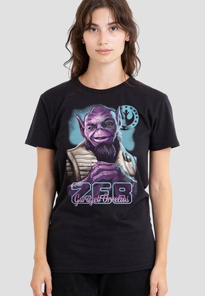 Young woman wearing a black T-shirt with a purple alien character and text "ZEB Garazeb Orrelios" on a plain gray background.