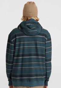 Capuchon sweatshirt in teal met horizontale strepen in grijs en bruin. Heeft een relaxte pasvorm en ribgebreide manchetten. Textiel met een zachte afwerking.