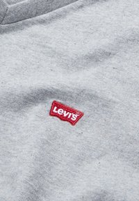 Siva bombažna majica z rdečim vezenim logotipom Levi's na levi strani prsnega koša. Mehka tekstura z obliko okroglega izreza.