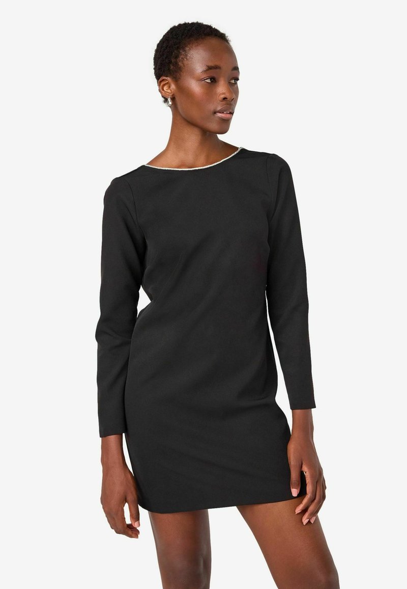 Svart långärmad klänning med rund halsringning, med en diskret kant. Slätt tyg och figursydd design, knälång. Minimalistisk stil.