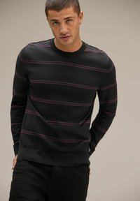 Svart tröja med horisontella lila ränder, ribbad rund halsringning och mudd; gjord av mjukt tyg, figurnära design med en slät textur.