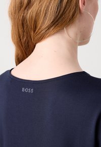 T-shirt navy con scollo rotondo, caratterizzato da un discreto logo "BOSS" ricamato in grigio sul retro. Tessuto liscio, design casual.