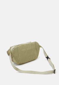 Bolso cruzado color caqui con forma rectangular, fabricado en tejido duradero. Incluye una amplia correa ajustable y un cierre con cremallera.