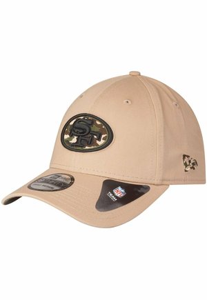 Cappellino da baseball color sabbia con visiera curva, dotato di un logo a toppa in camouflage e dettagli nei punti di cucitura. L'etichetta mostra la taglia e il marchio NFL.
