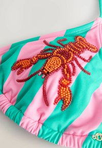 Top de bikini con tejido a rayas rosas y verdes, detallado con un diseño de langosta de cuentas en naranja y rojo, con bordes fruncidos y detalles metálicos.