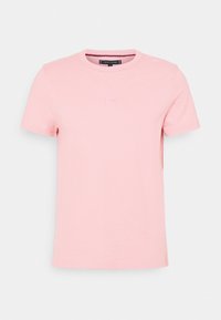 Camiseta de algodón rosa con cuello redondo, mangas cortas y un sutil detalle de logo en el centro. Textura suave y corte regular.