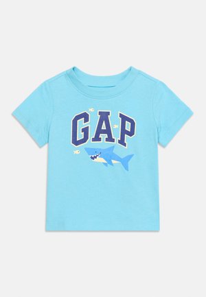 Lyseblå småbørn t-shirt med teksten "GAP", en tegneseriehaj og små fisk trykt på forsiden.