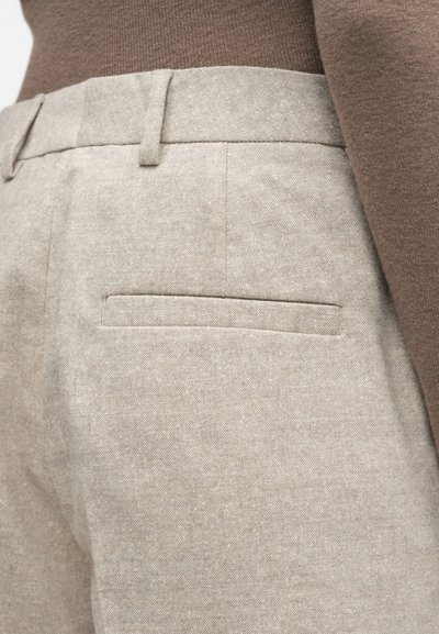 Svijetlosmeđe krojene hlače od teksturirane tkanine, s glatkim pojasom i jednom stražnjom džepnom detalj.