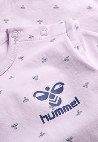Lys lilla bomuldsbody med små blå bi-mønstre og et fremtrædende navy logo med "hummel" på forsiden. Trykknaplukninger ved halsen.