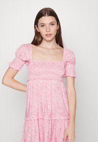 Vestido rosa com decote quadrado, mangas bufantes e saia em camadas. Apresenta um padrão de riscas de zebra e um corpete franzido.