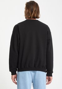 Sort sweatshirt lavet af blødt stof, med rund halsudskæring, ribbede manchetter og kant, i en afslappet pasform uden synlige logoer eller mønstre.
